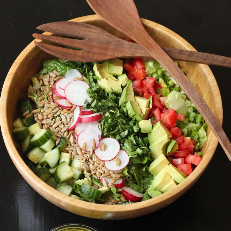 wooden bowl of chopped salad with wooden serving ware.