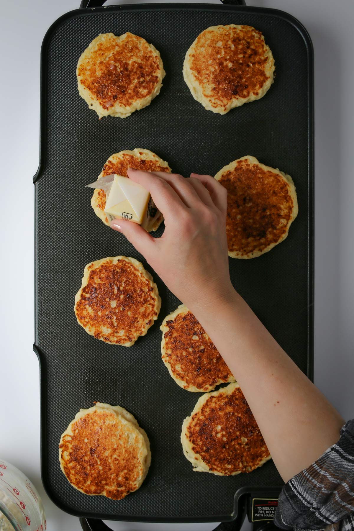 buttering pancakes for dinner with a stick of butter.