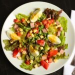 overhead shot of ham and cheese salad with french vinaigrette dressing drizzled over top.