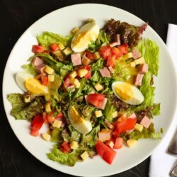 overhead shot of ham and cheese salad with french vinaigrette dressing drizzled over top.