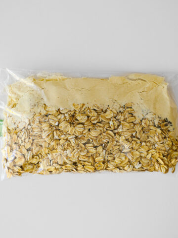 Plastic sandwich bag made into instant oatmeal packet on white counter.