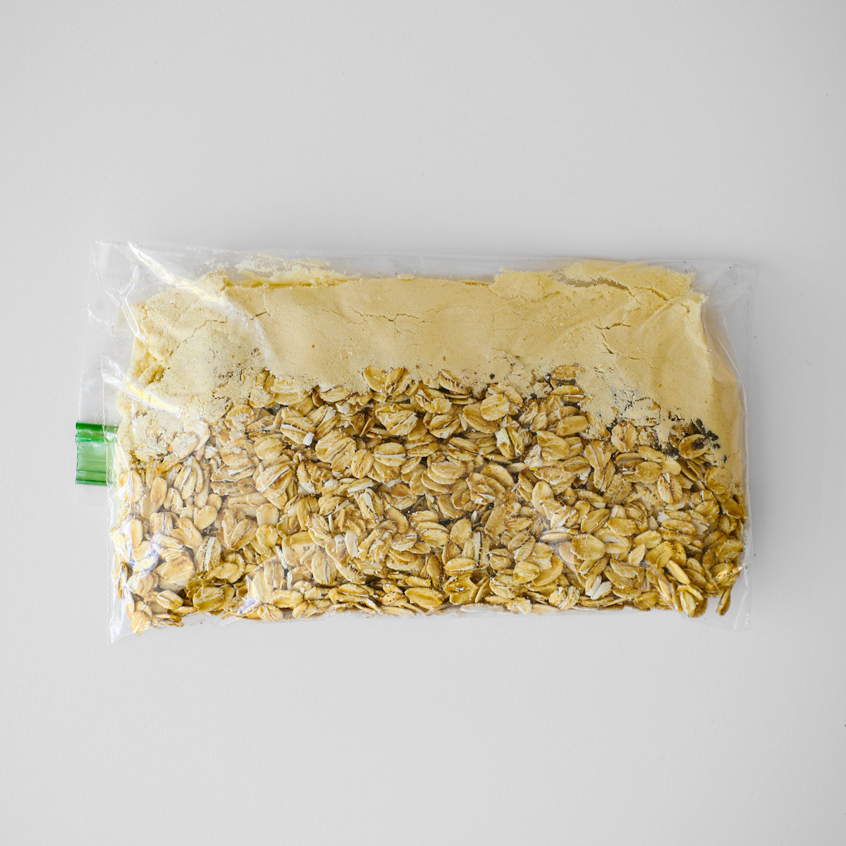 Plastic sandwich bag made into instant oatmeal packet on white counter.