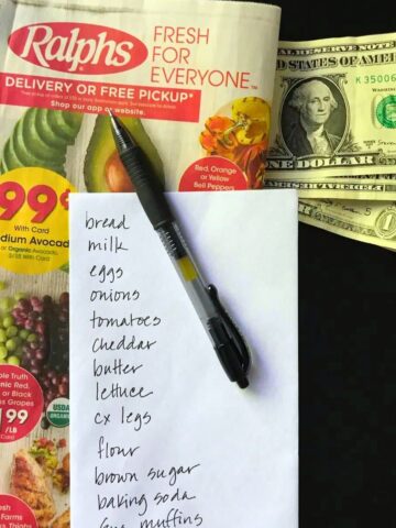 grocery store ad with shopping list, pen, and dollar bills.
