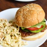 sausage burger on plate with pile of coleslaw.