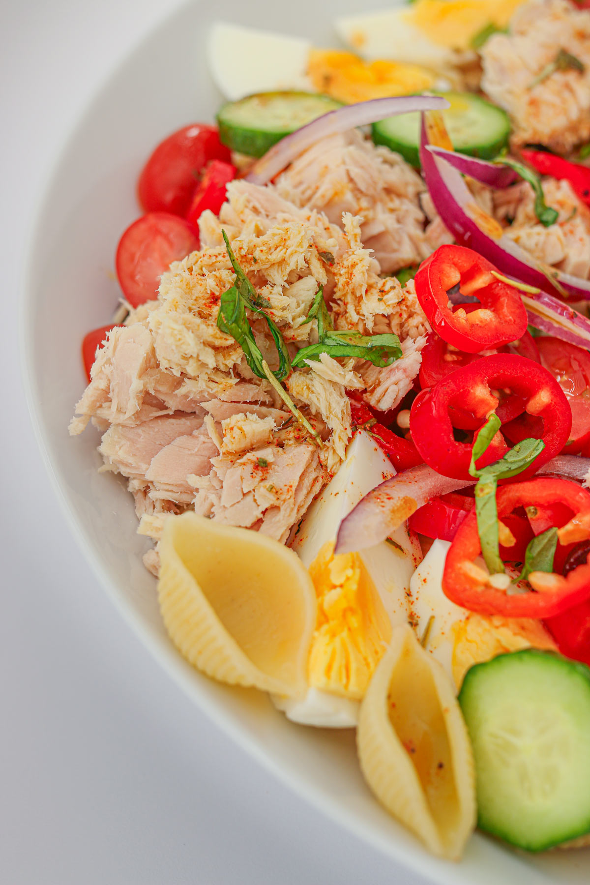 close up of pasta salad with flaky canned tuna and fresh herbs.
