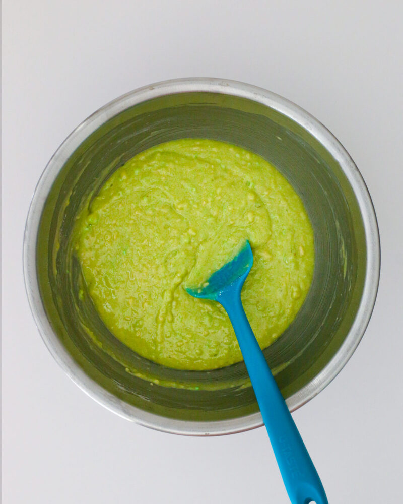 the green batter in a bowl with a rubber spatula.