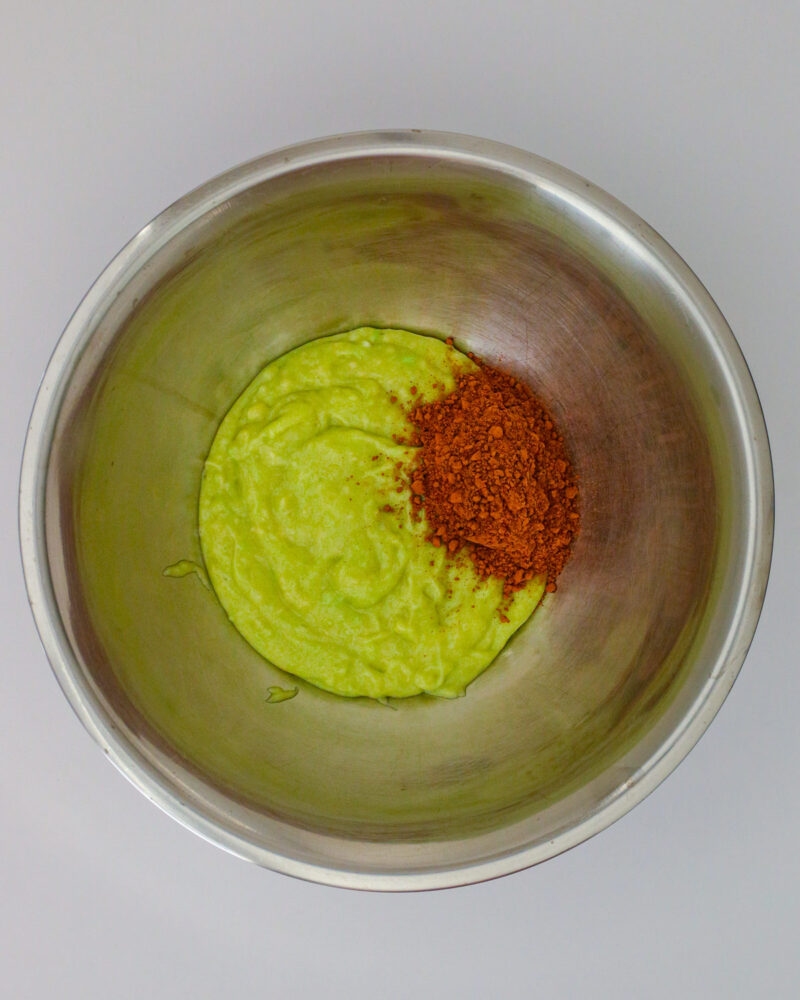 adding cocoa powder to a bit of green batter in a metal bowl.