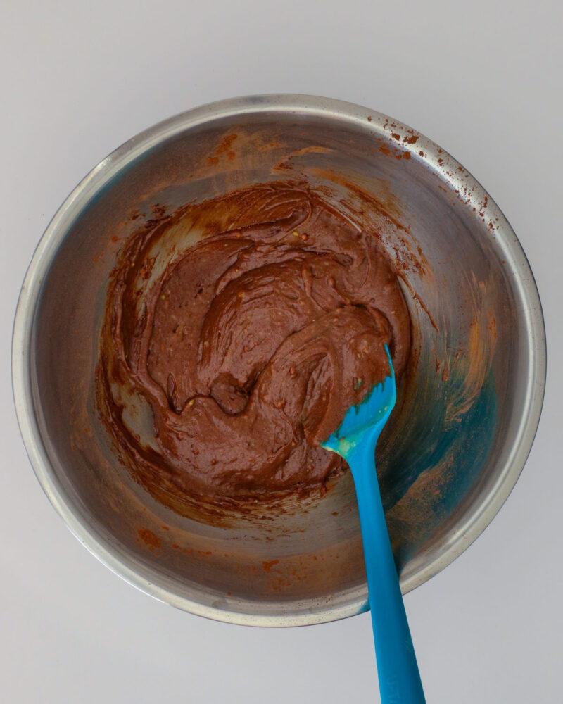 the chocolate batter in a metal bowl with a rubber spatula.
