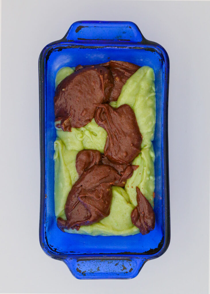 the green and chocolate batters alternating in the loaf pan.