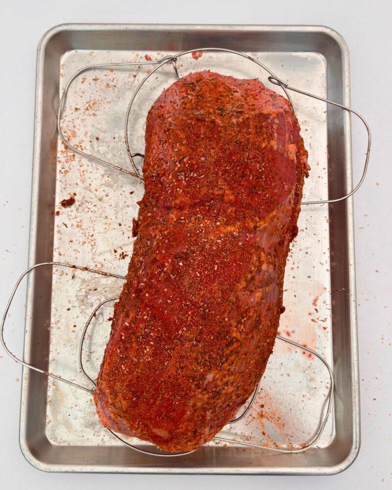 seasoned roast beef on racks in sheet pan.