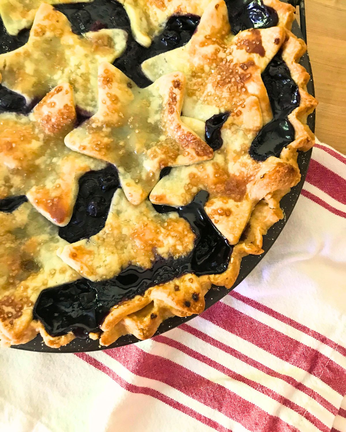 berry pie with star pastry cut outs next to a red striped cloth.