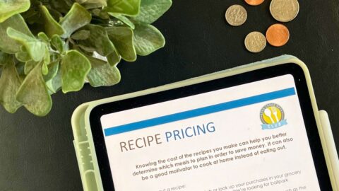 close up of recipe pricing worksheet near plant and coins.