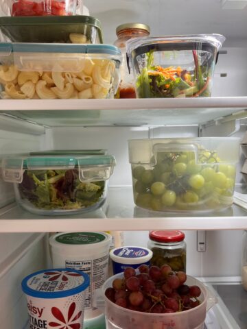 clear containers of food on shelves of refrigerator.